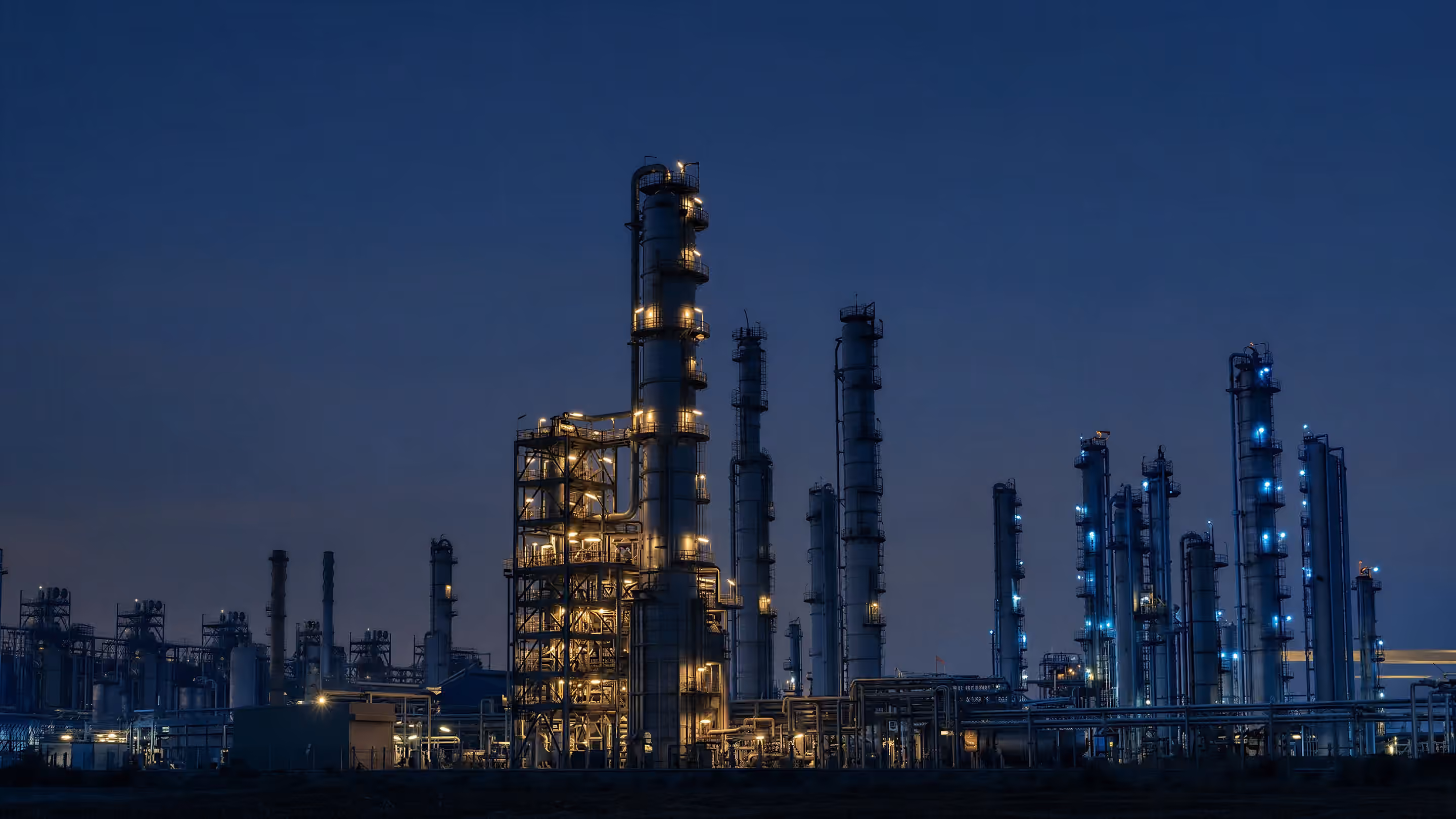 Process plant lit at night, with distillation columns and pipe racks