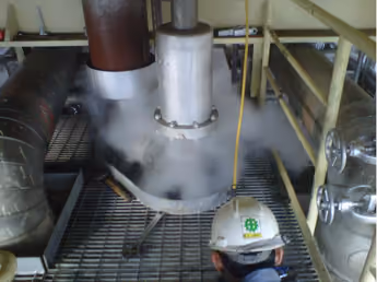 Safety valve discharging steam during a pop-up test, watched by a technician in a KEI hard hat