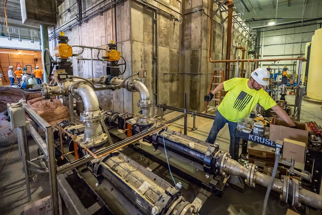 Technician working on pipework and valves inside a plant